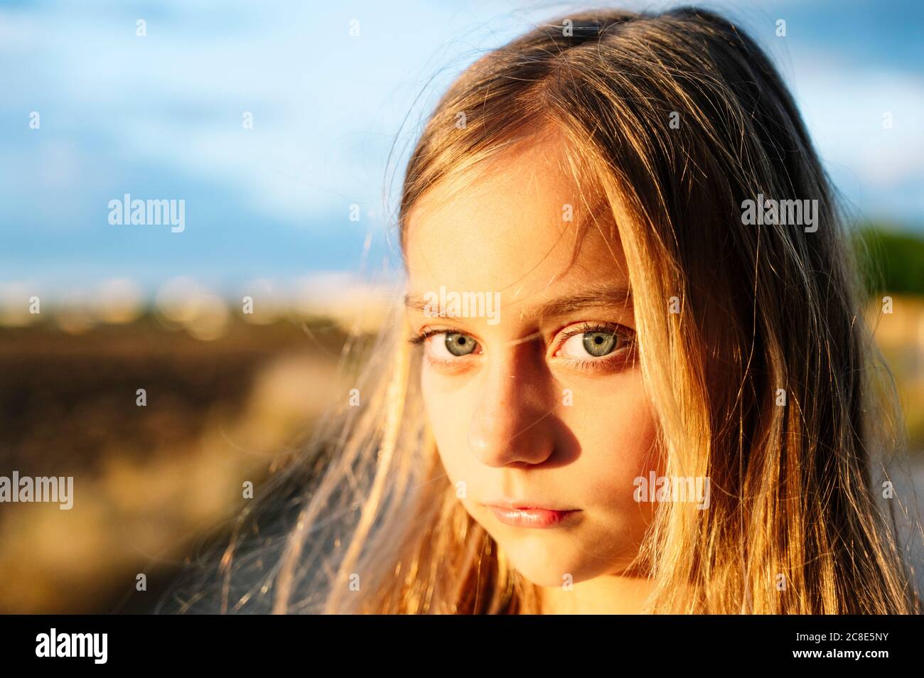 Blonde fille regardant avec la lumière du soleil sur son visage Banque D'Images
