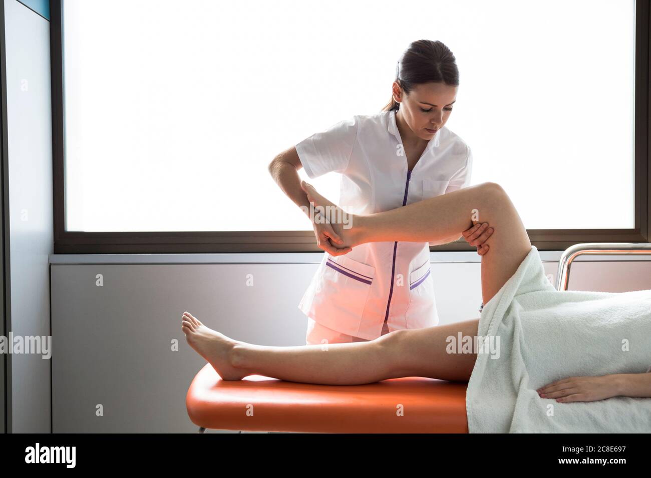 Physiothérapeute femme traitant la jambe de la patiente Banque D'Images