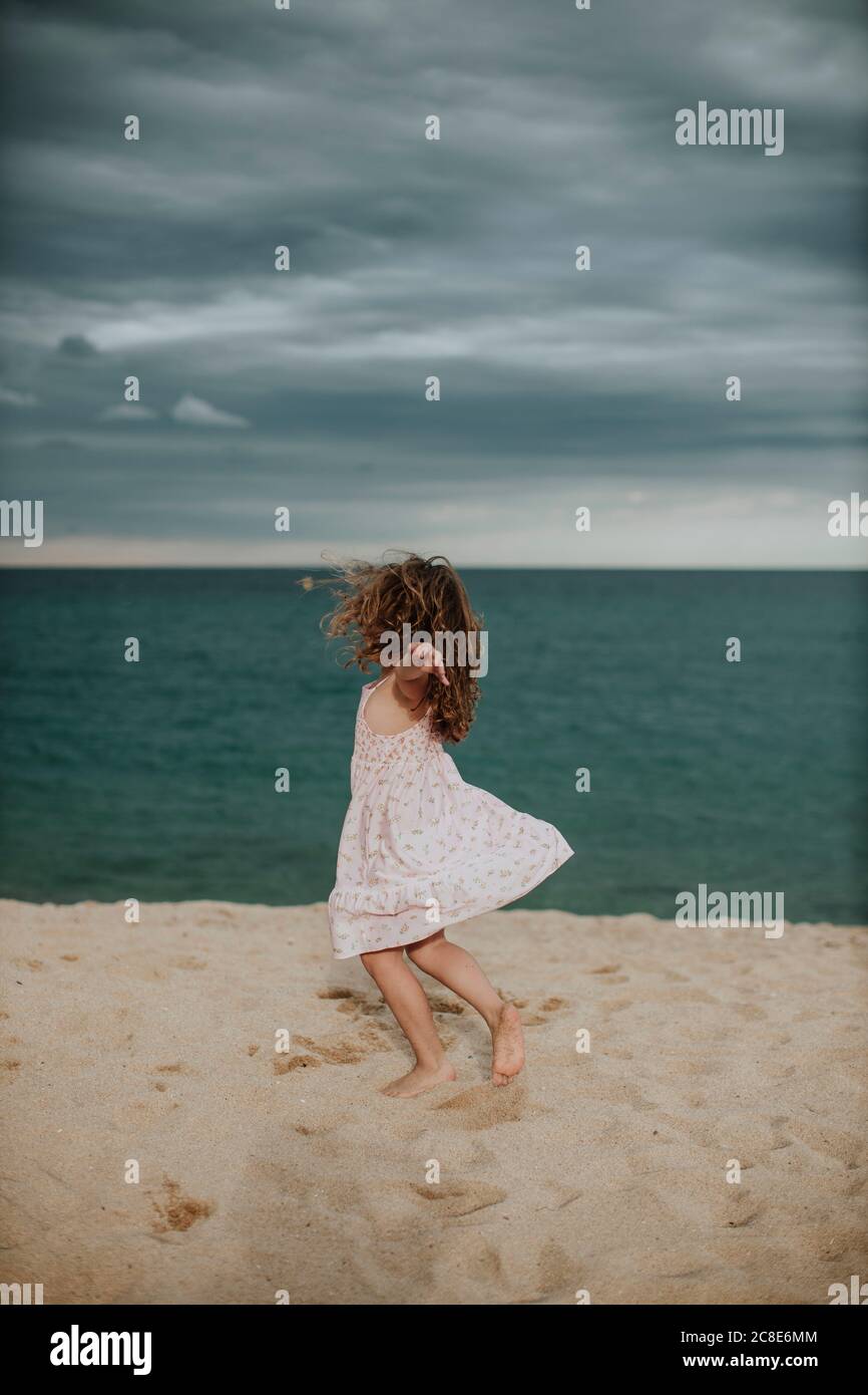 Une fille insouciante dansant sur le sable contre la mer Banque D'Images