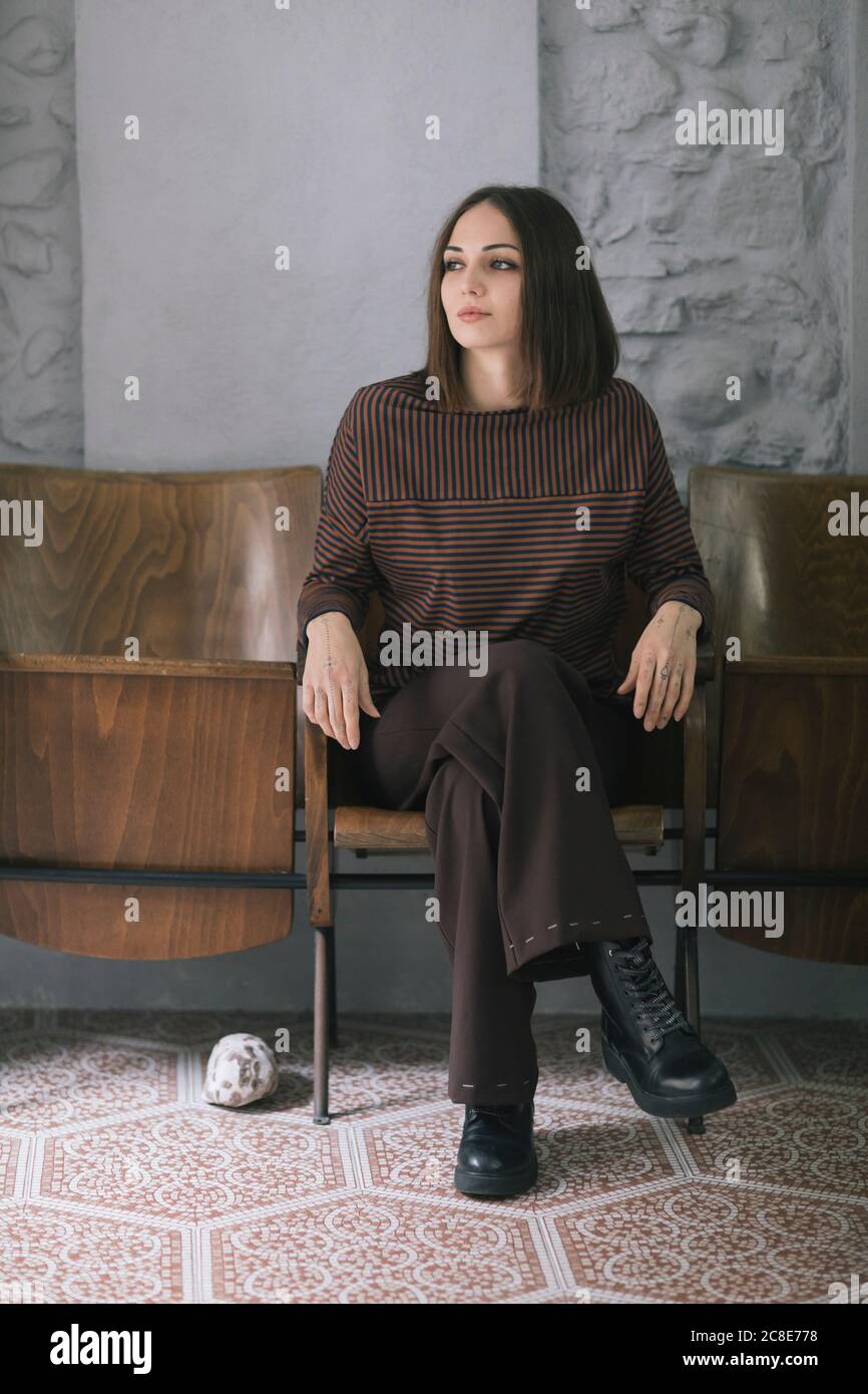 Belle femme attentionnés assise sur une chaise dans un studio de design de vêtements Banque D'Images