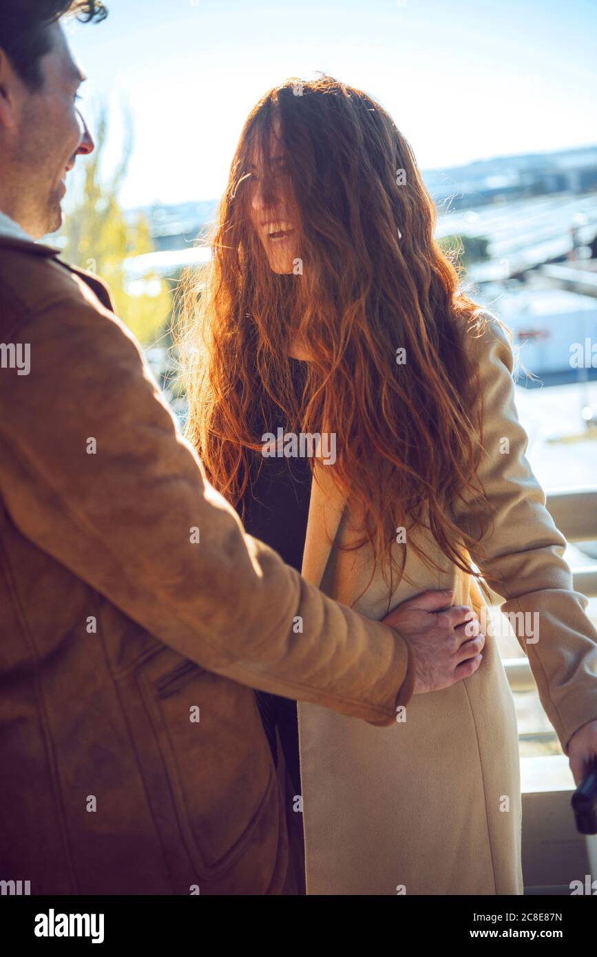 Gaie longue rouge cheveux femme debout avec un petit ami pendant le soleil jour Banque D'Images
