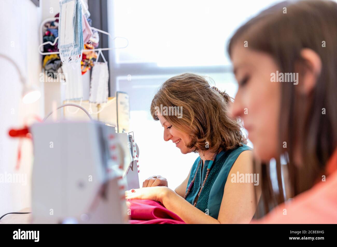 Couturière souriante couture par un collègue au studio de design Banque D'Images