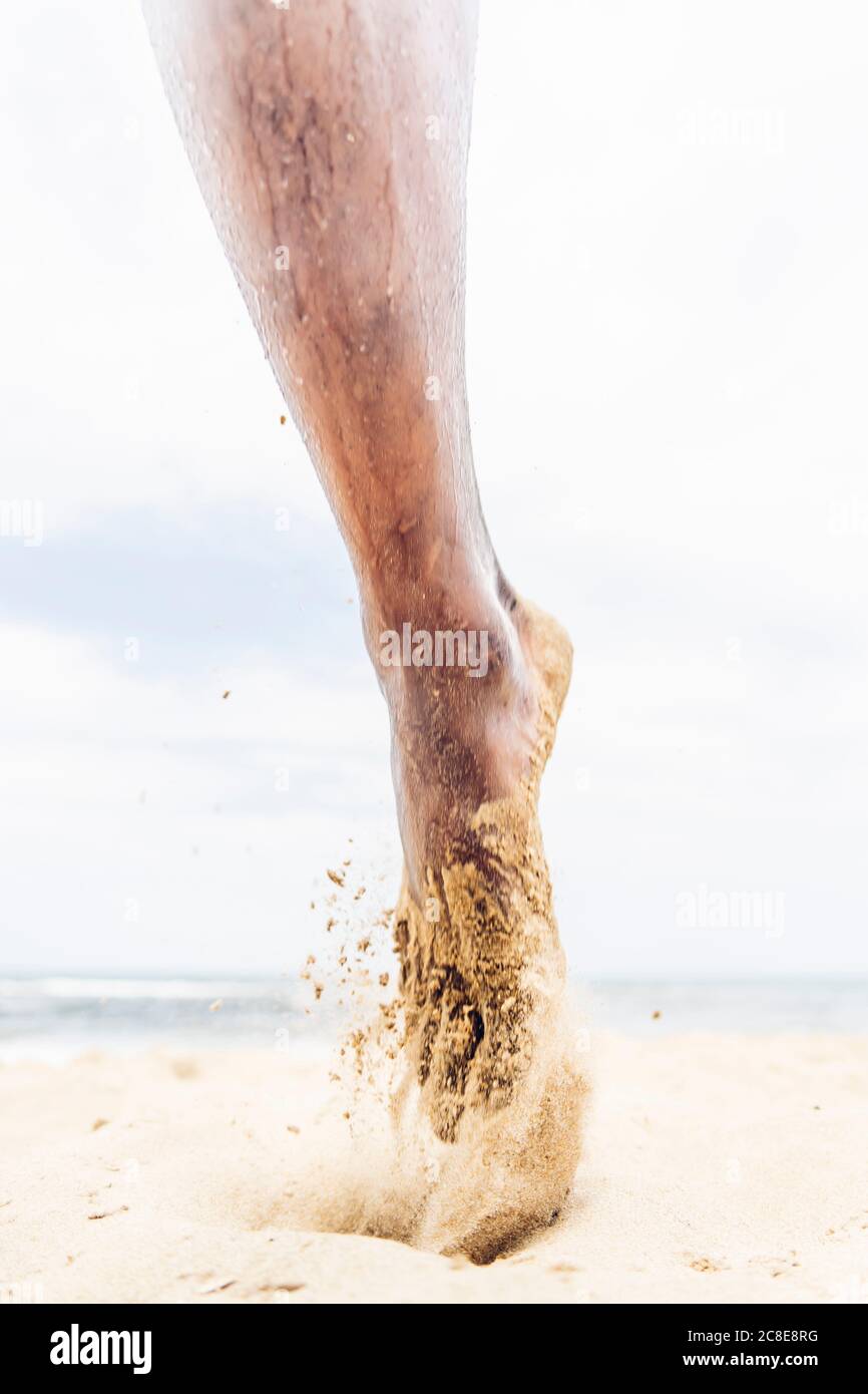 Pied de sable de l'homme de course sur la plage Banque D'Images