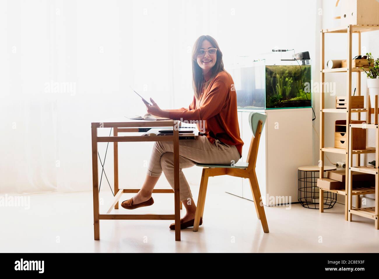 Femme indépendante travaillant à la maison assise au bureau à l'aide d'une tablette Banque D'Images