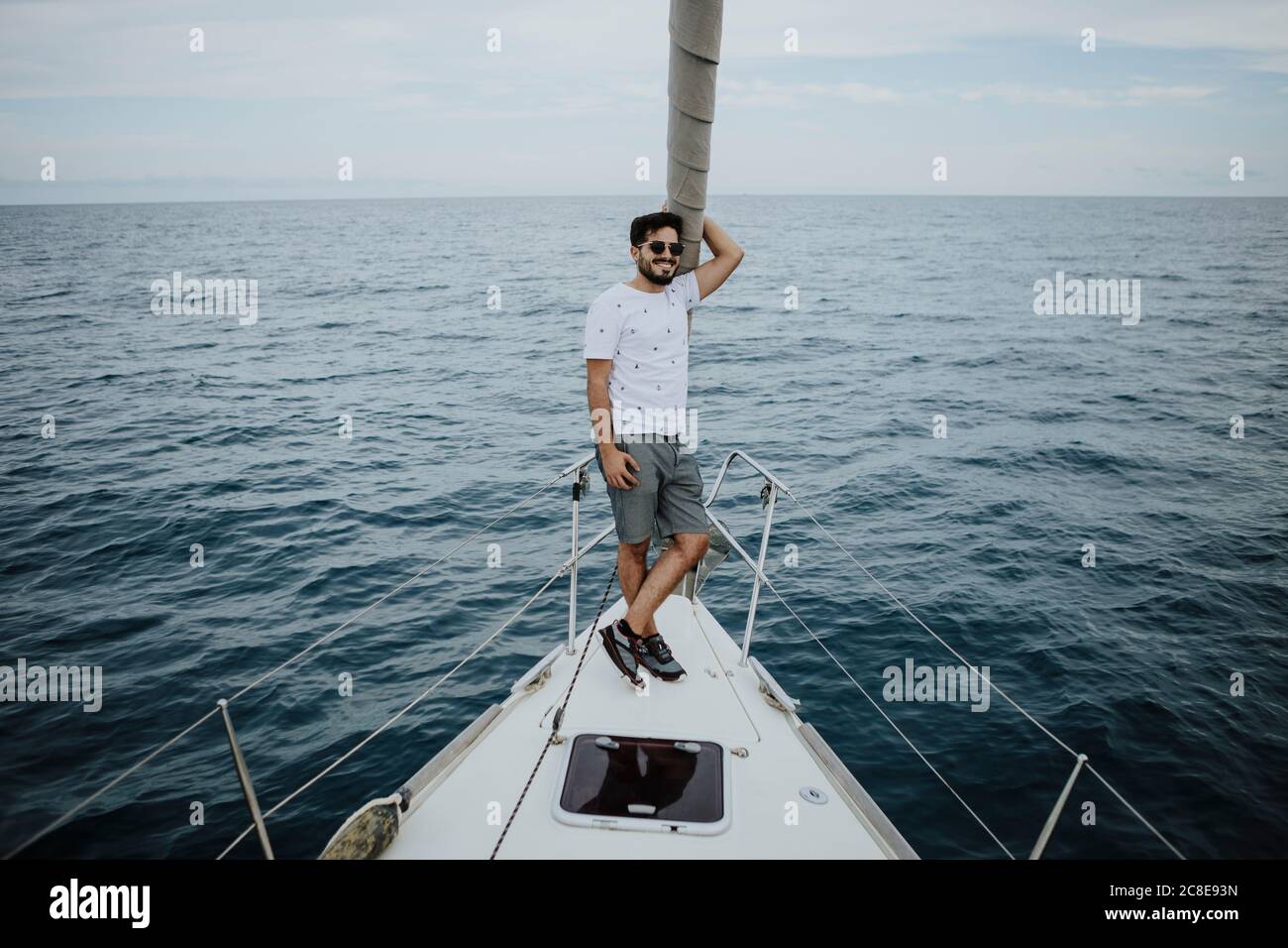 Homme marin portant des lunettes de soleil debout sur l'arc du voilier mer Banque D'Images