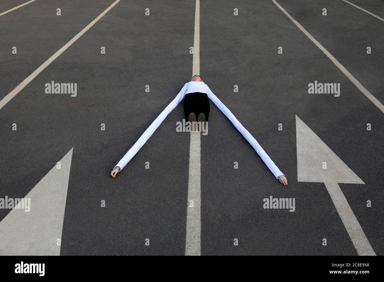 Femme avec de longues mains artificielles au milieu des symboles de flèche sur route Banque D'Images