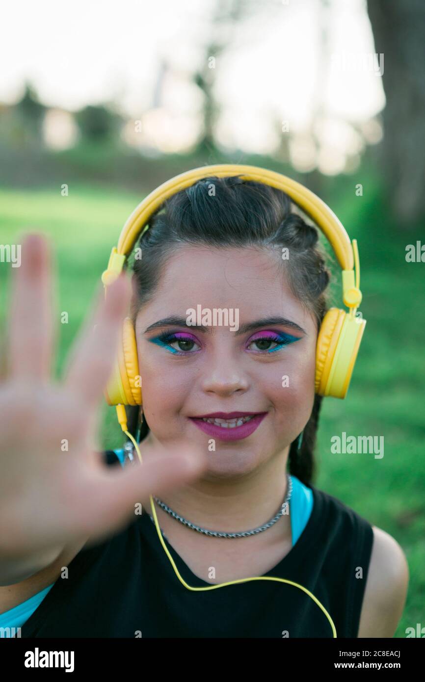 Adolescente avec le syndrome de Down portant 8s coloré maquillage et écouter de la musique avec un casque jaune Banque D'Images