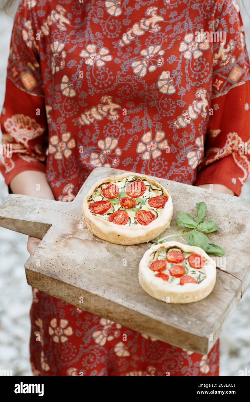 Gros plan de la jeune femme portant une tarte salée sur le plateau de service en vous tenant à l'extérieur Banque D'Images Gros plan de la jeune femme portant une tarte salée sur le plateau de service en vous tenant à l'extérieur Banque D'Images