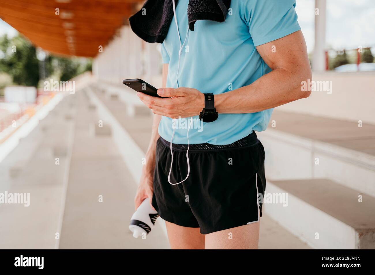 Athlète masculin vérifiant le smartphone sur la tribune dans le stade Banque D'Images