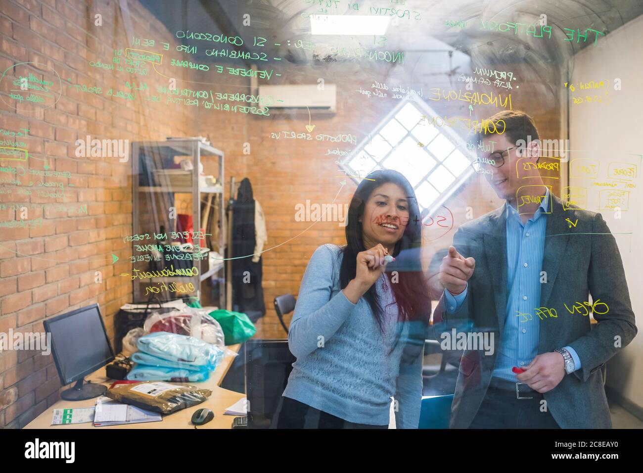 Homme d'affaires et femme remue-méninges en train de prendre des notes sur le verre bureau Banque D'Images