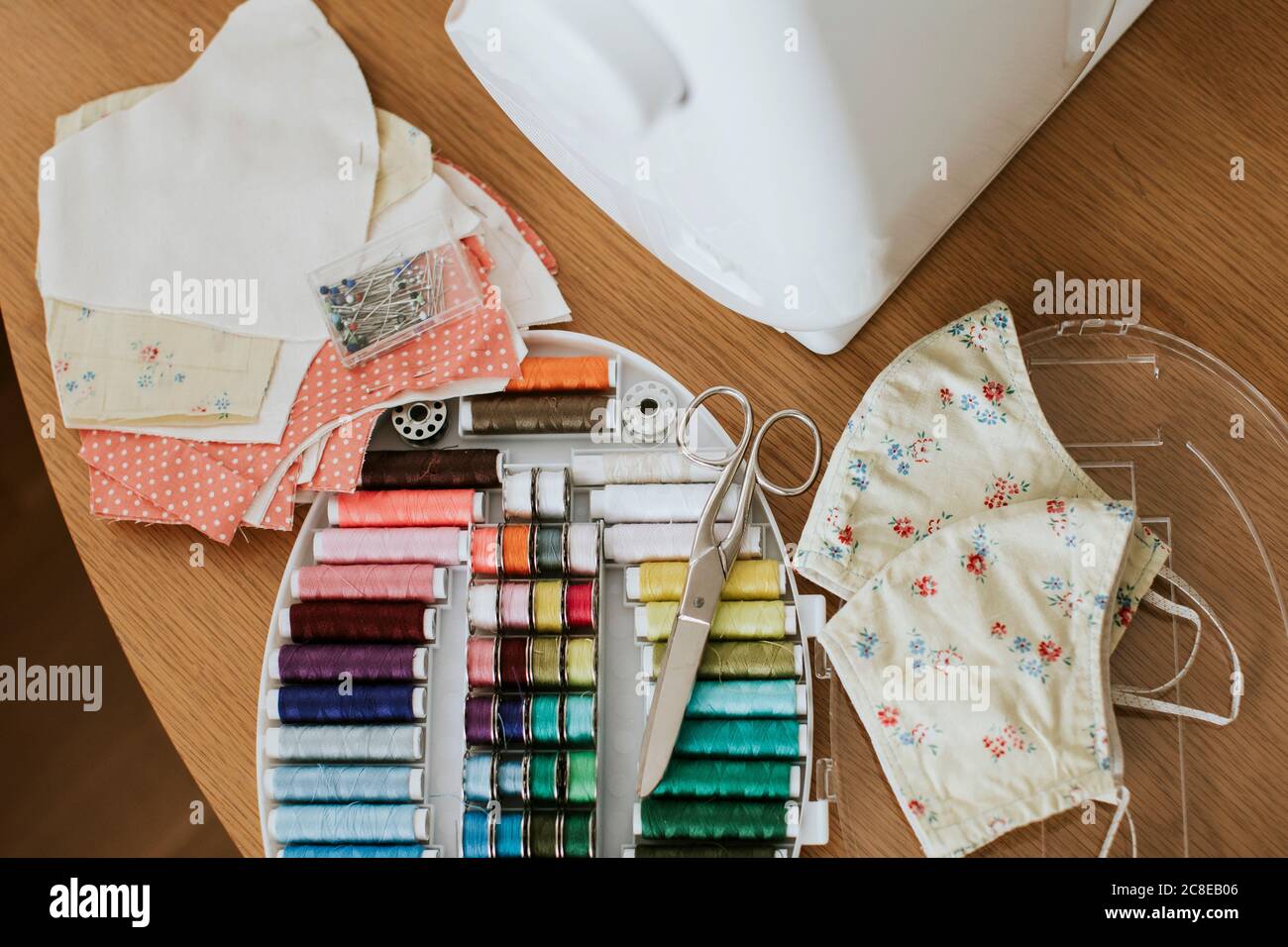 Masques faciaux fleuris avec articles de couture sur la table à la maison Pendant COVID-19 Banque D'Images