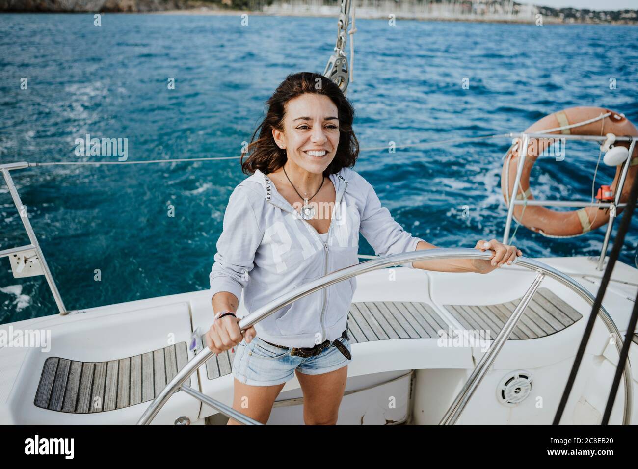Une femme souriante navigue en voilier sur mer Banque D'Images