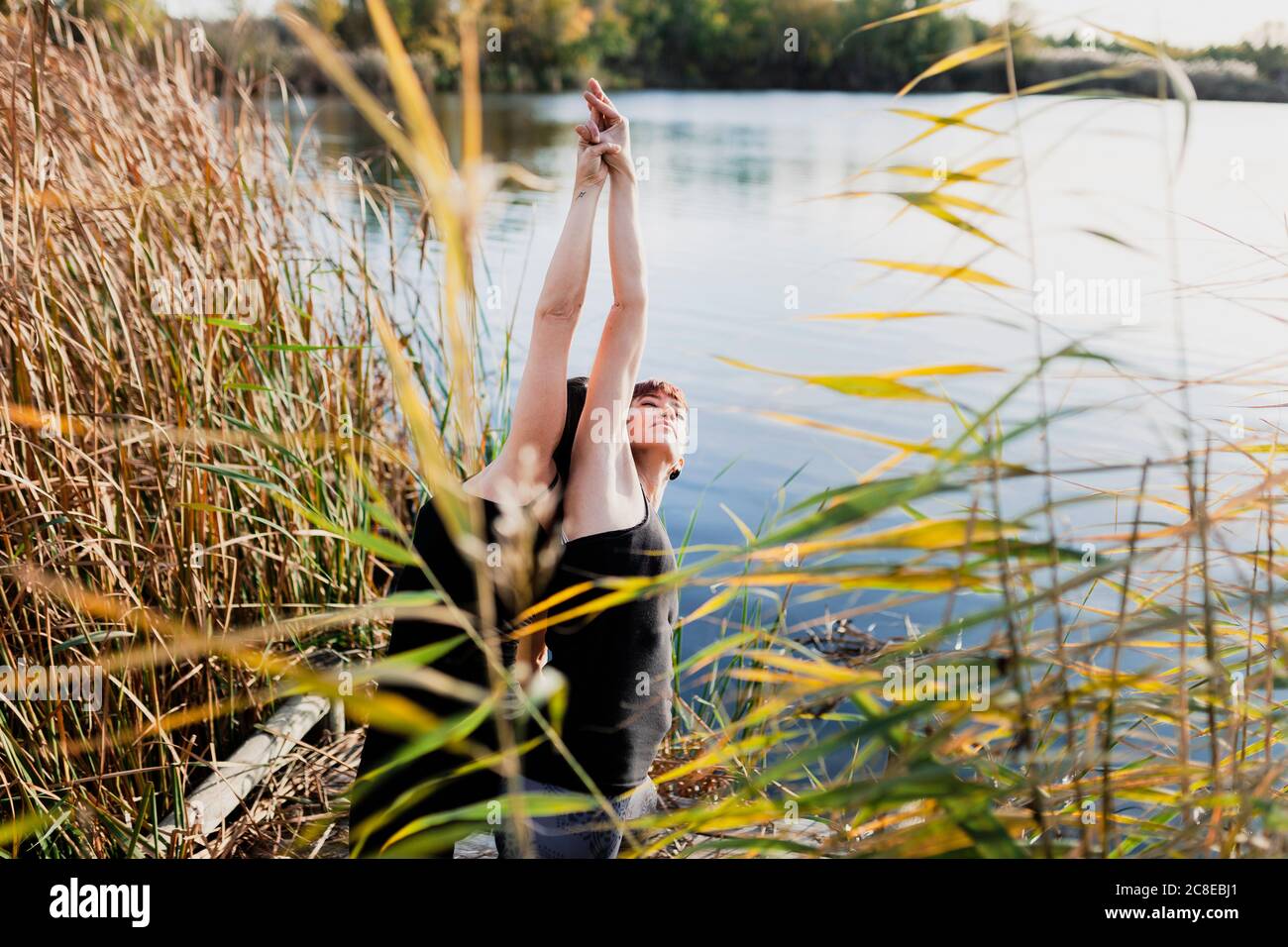 Des amies pratiquant le yoga debout au bord du lac Banque D'Images