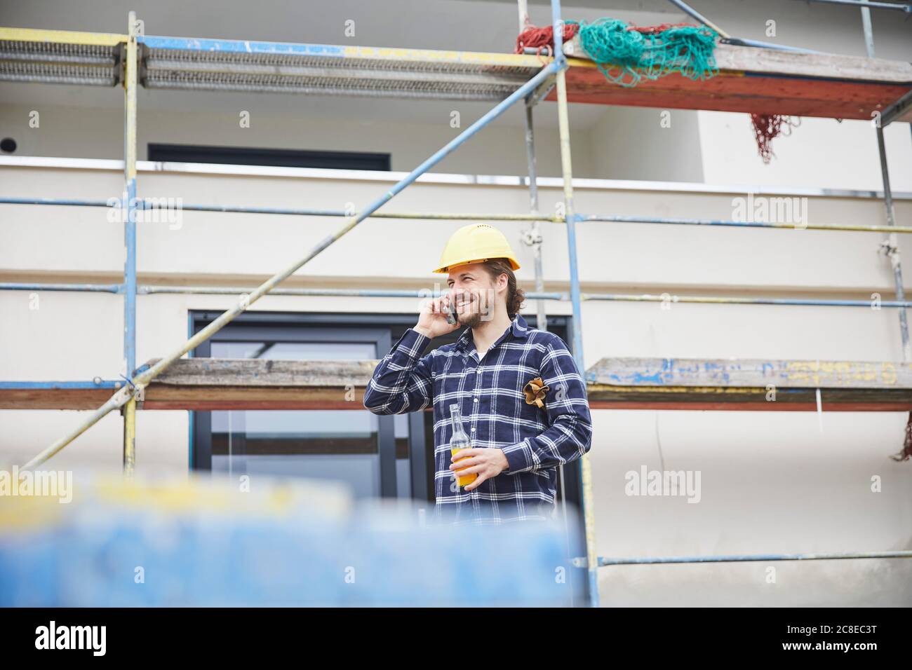 Travailleur souriant au téléphone un chantier de construction Banque D'Images