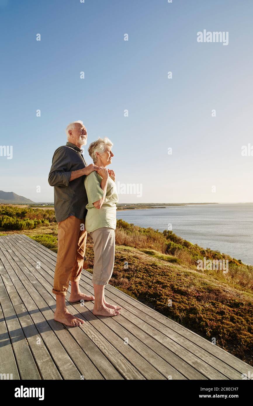 Couple senior offrant la vue sur la terrasse en bois du mer Banque D'Images