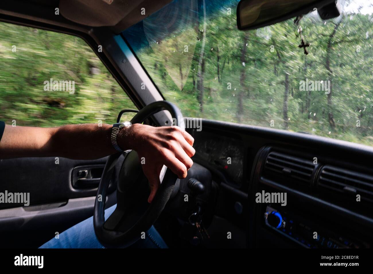 Main de l'homme sur le volant pendant le trajet sur route Banque D'Images