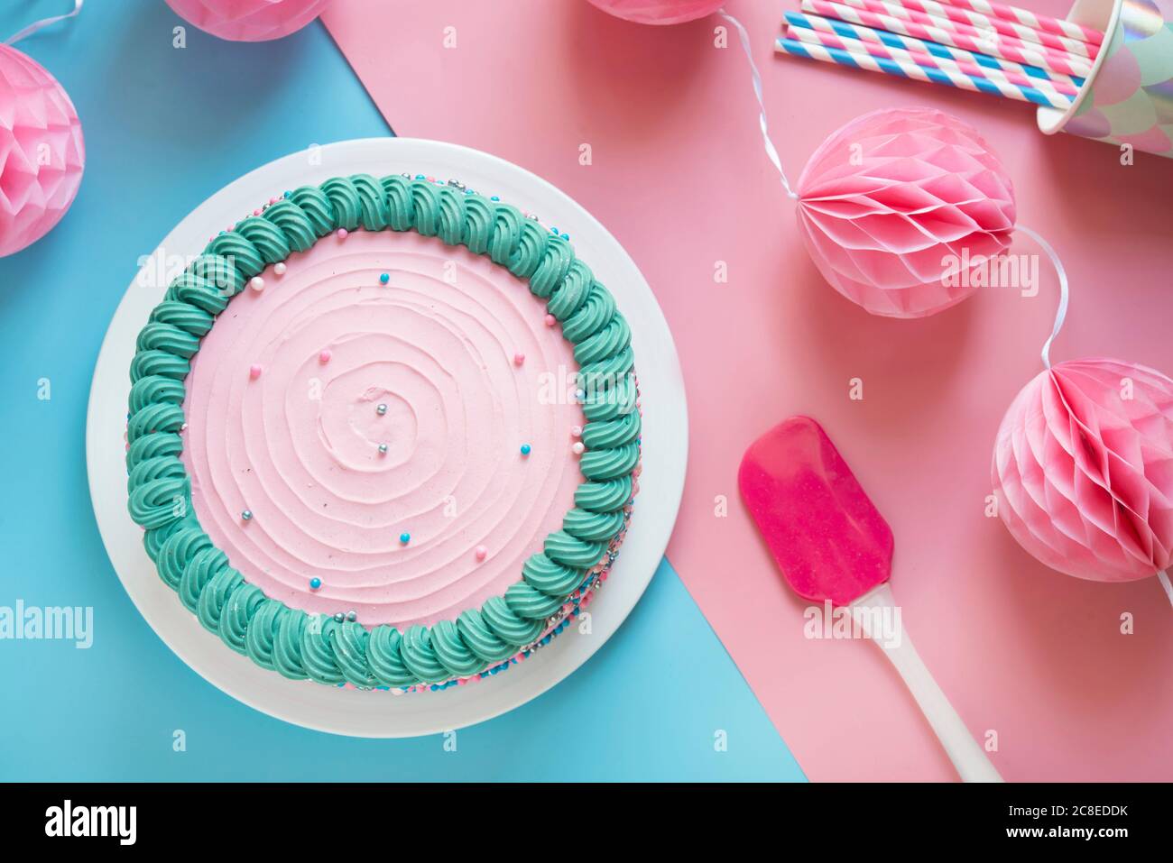 Photo de studio de gâteau d'anniversaire rose et de décorations de fête en papier Banque D'Images