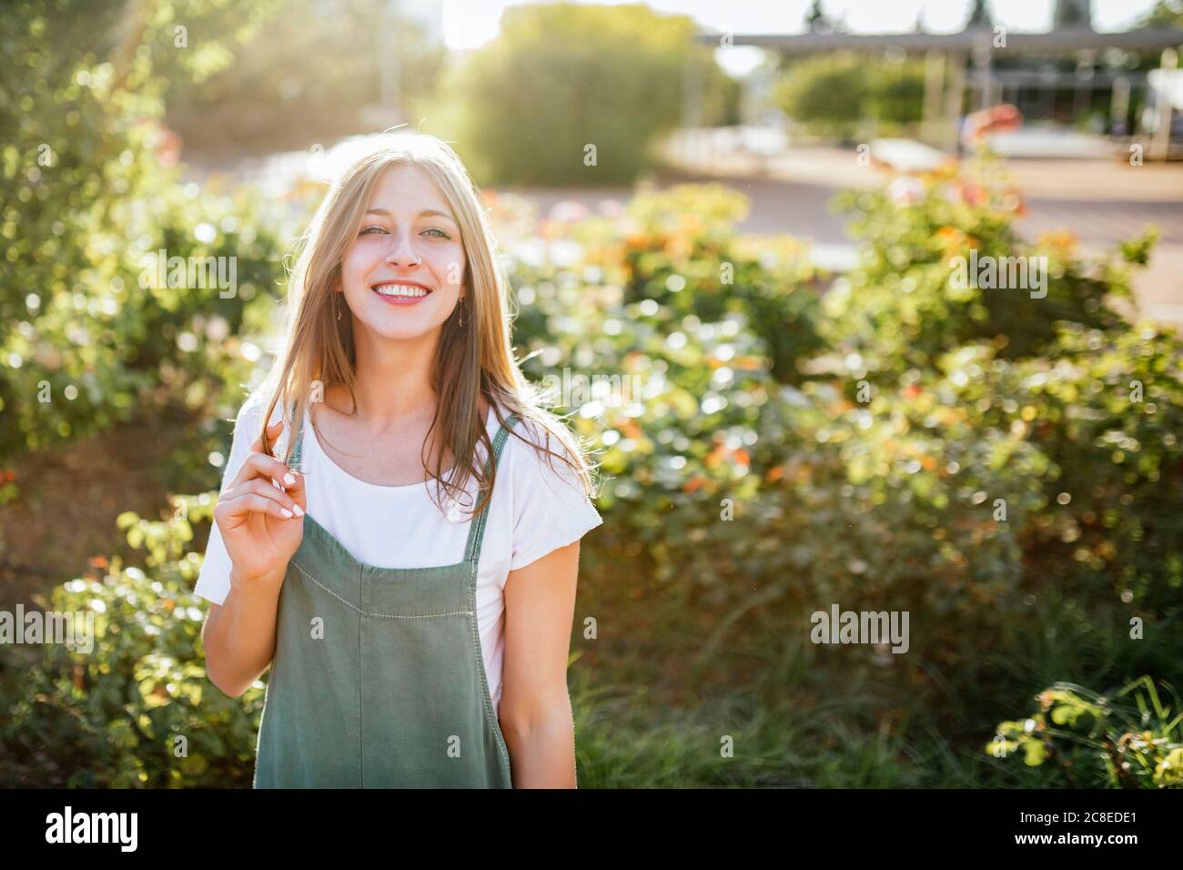 Portrait de jeune femme souriante dans le jardin public à contre-jour Banque D'Images