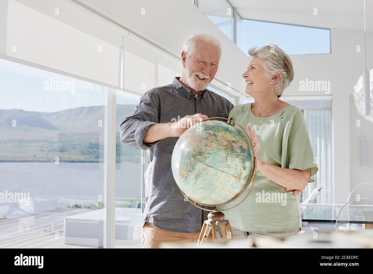 Couple senior heureux avec globe dans une villa de luxe Banque D'Images