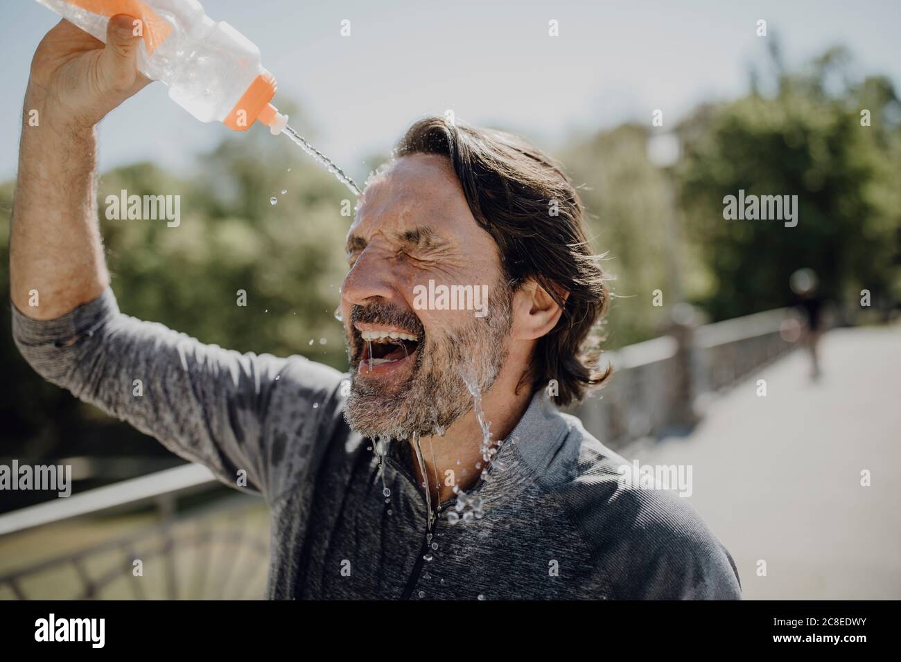 Gros plan d'un homme mature qui verse de l'eau sur le visage dans le parc par beau temps Banque D'Images