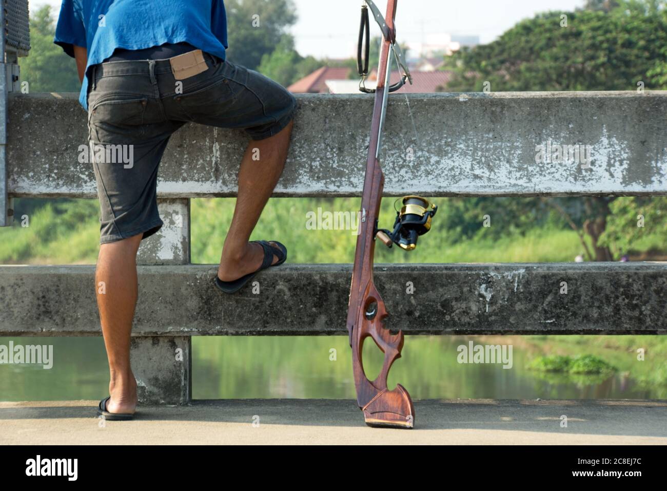 Homme thaïlandais à la recherche de poissons de jour sur le pont avec un fer de lance en bois près de Ratchaburi, Thaïlande. Banque D'Images