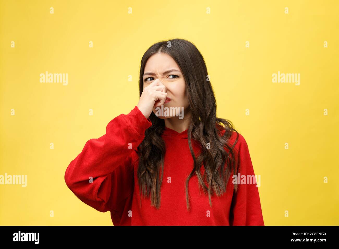 Odeur désagréable. La jeune femme déguste l'odeur isolée sur fond jaune. Banque D'Images