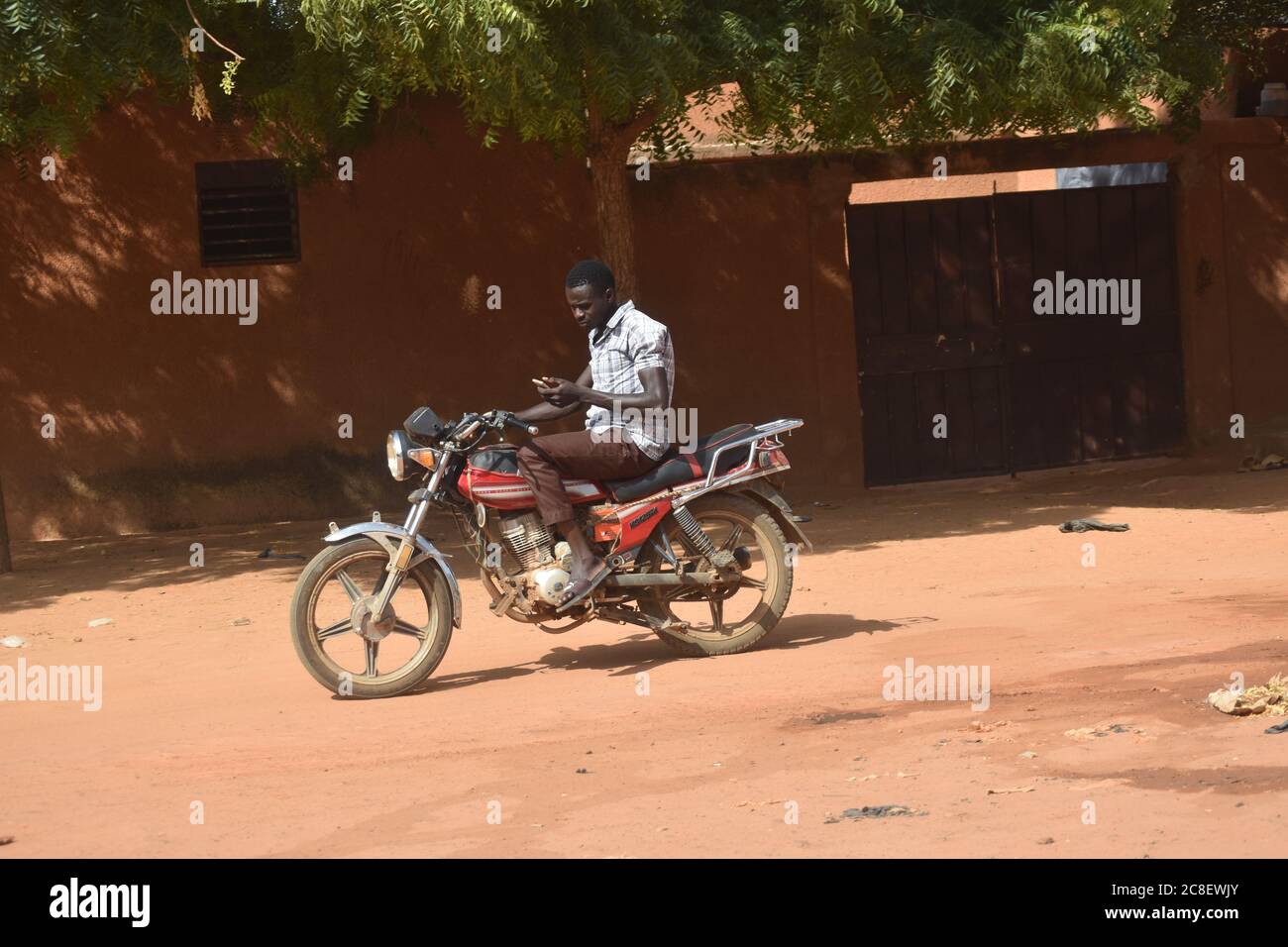 Un homme sur une moto, sans casque, textant en conduisant, au Niger, en Afrique Banque D'Images