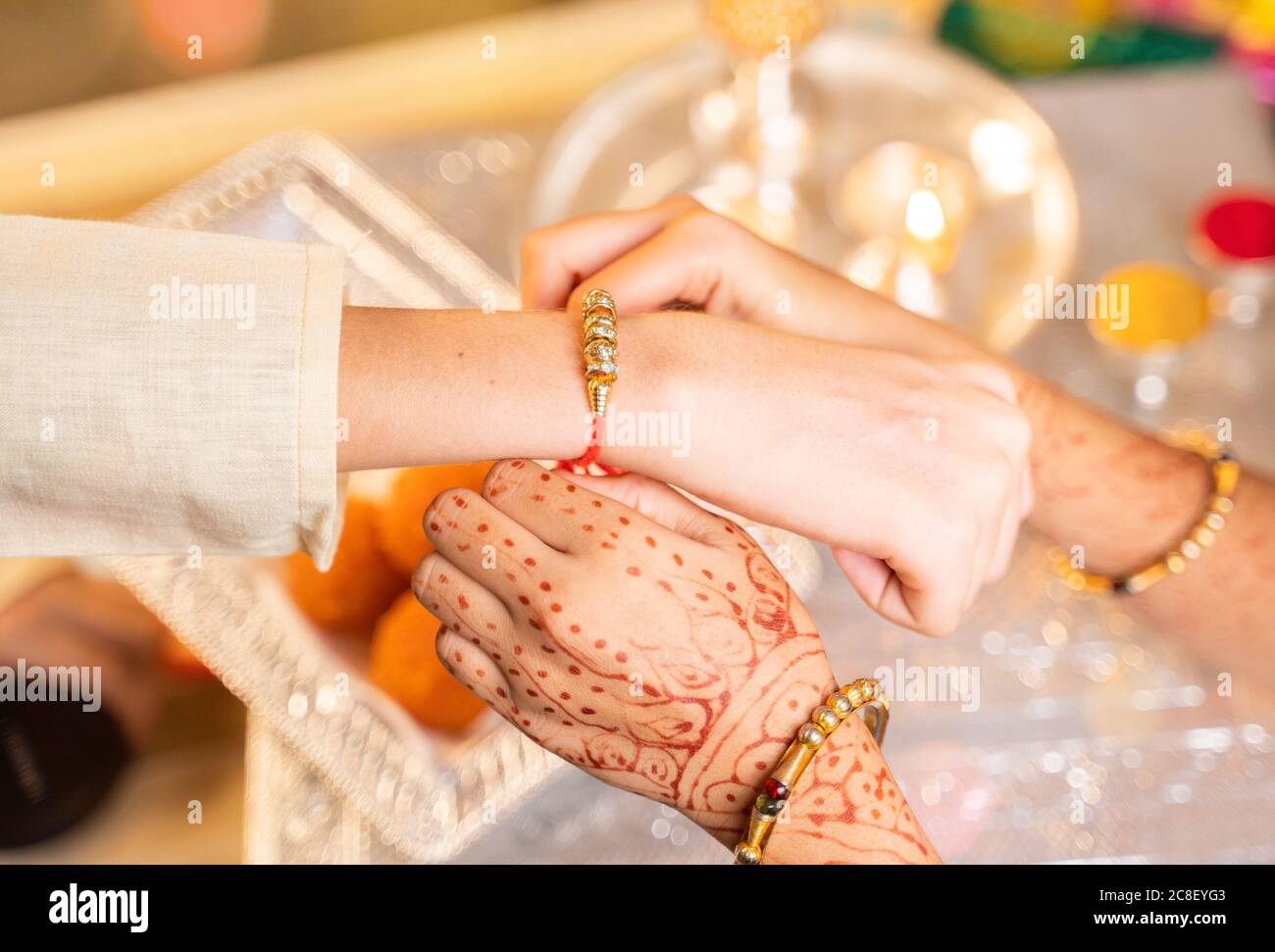 Gros plan des mains, sœur qui lie rakhi, Raksha bandhan au poignet de son frère pendant le festival ou la cérémonie - Rakshabanghan a célébré à travers l'Inde comme Banque D'Images