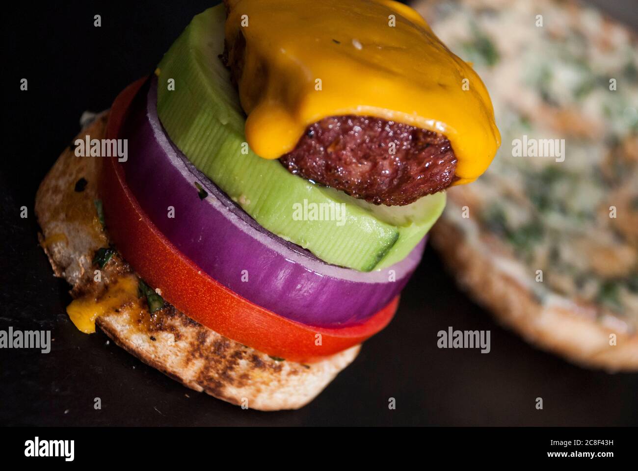 Hamburger avocat avec tranche d'oignon rouge, Bun hamburger et tomate sur fond en bois Banque D'Images