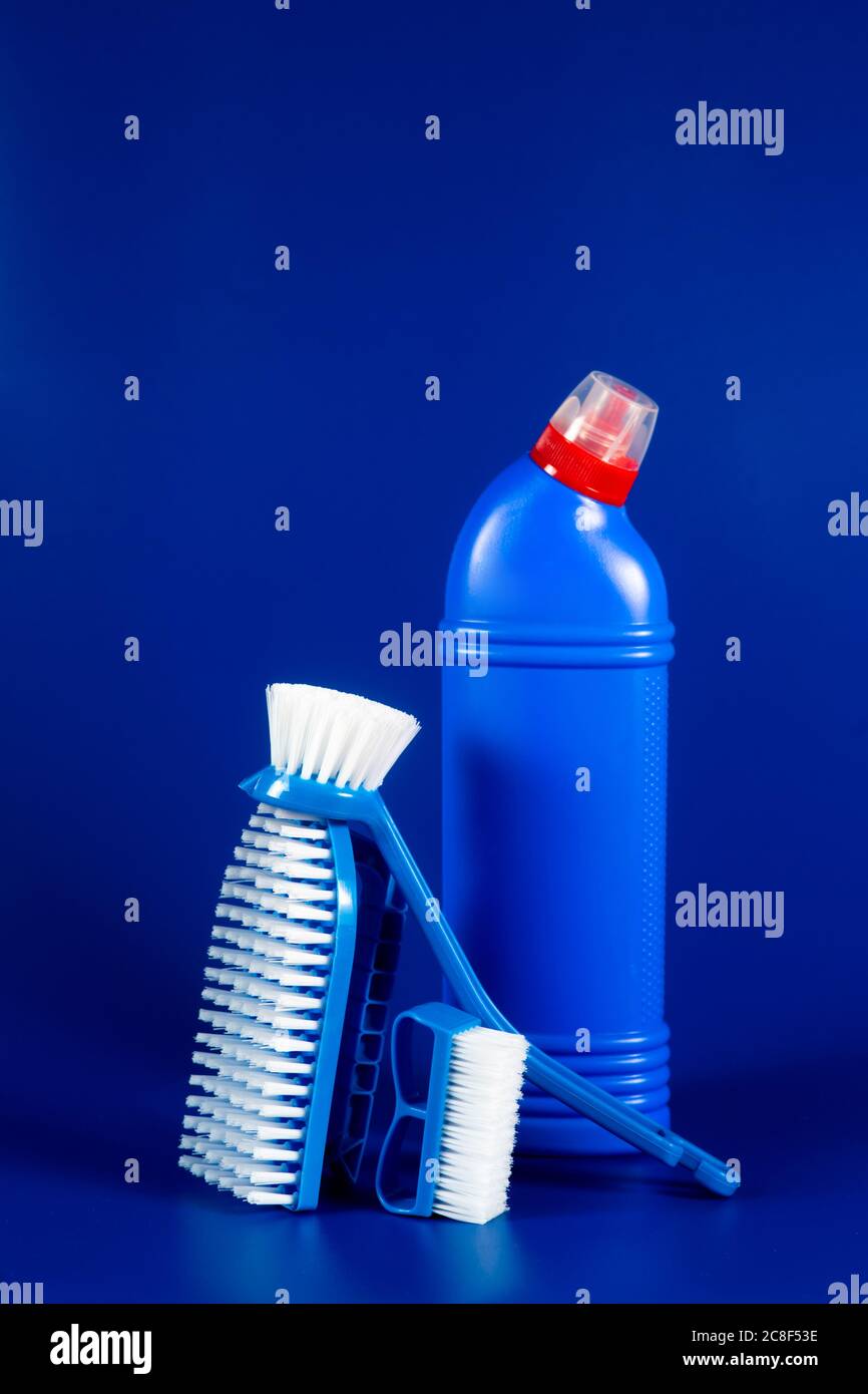 Bouteille bleue avec détergent en poudre et brosses sur fond bleu, espace pour le texte. Banque D'Images