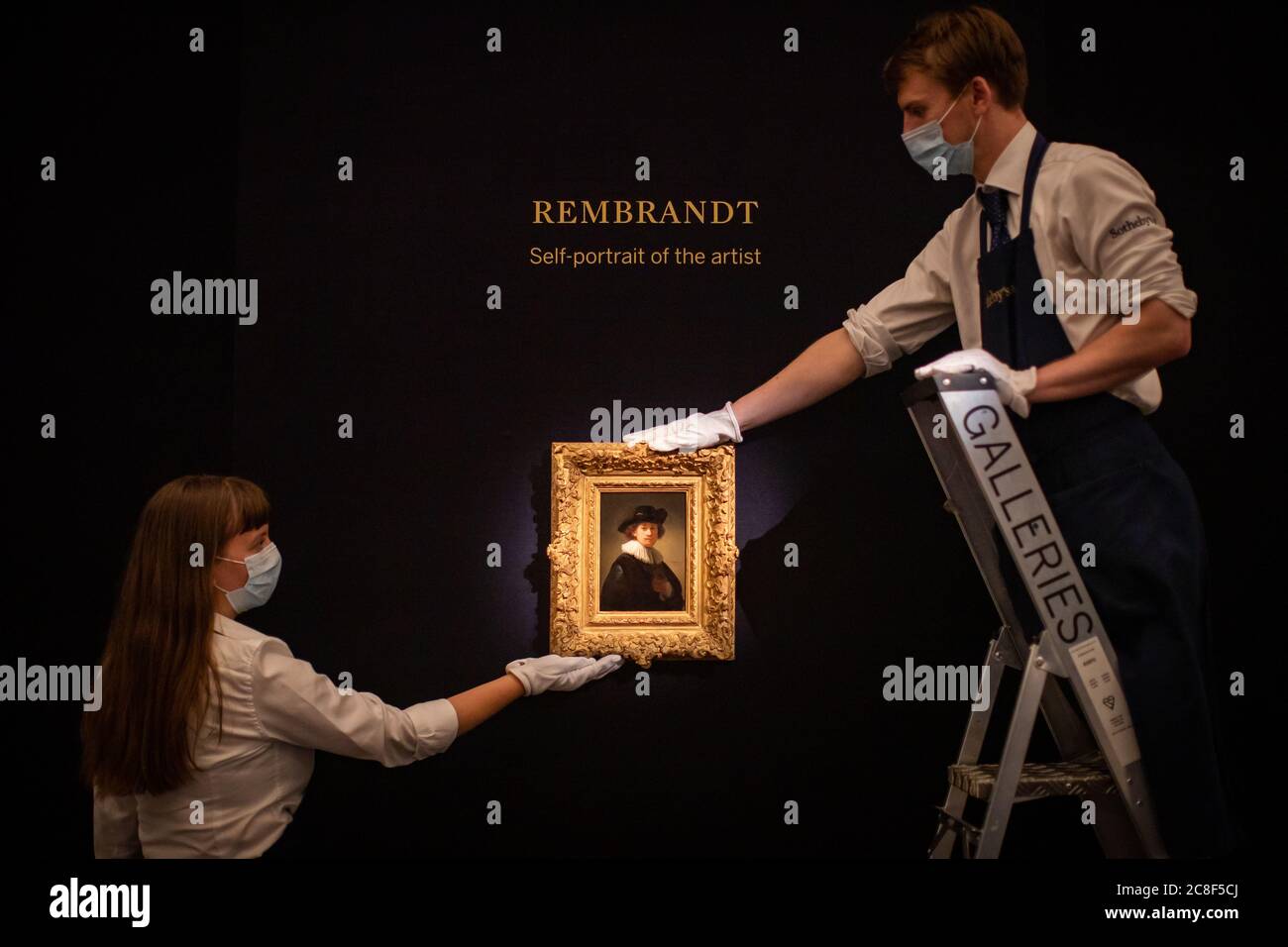 Assistants de galerie devant le autoportrait, portant un chapeau de rouff et noir de Rembrandt, 1632, huile sur panneau de chêne avec une estimation de 12-16 millions de GBP lors d'un aperçu de presse à Sotheby's à Londres en prévision de leur vente de «Rembrandt à Richter» le 28 juillet. Banque D'Images