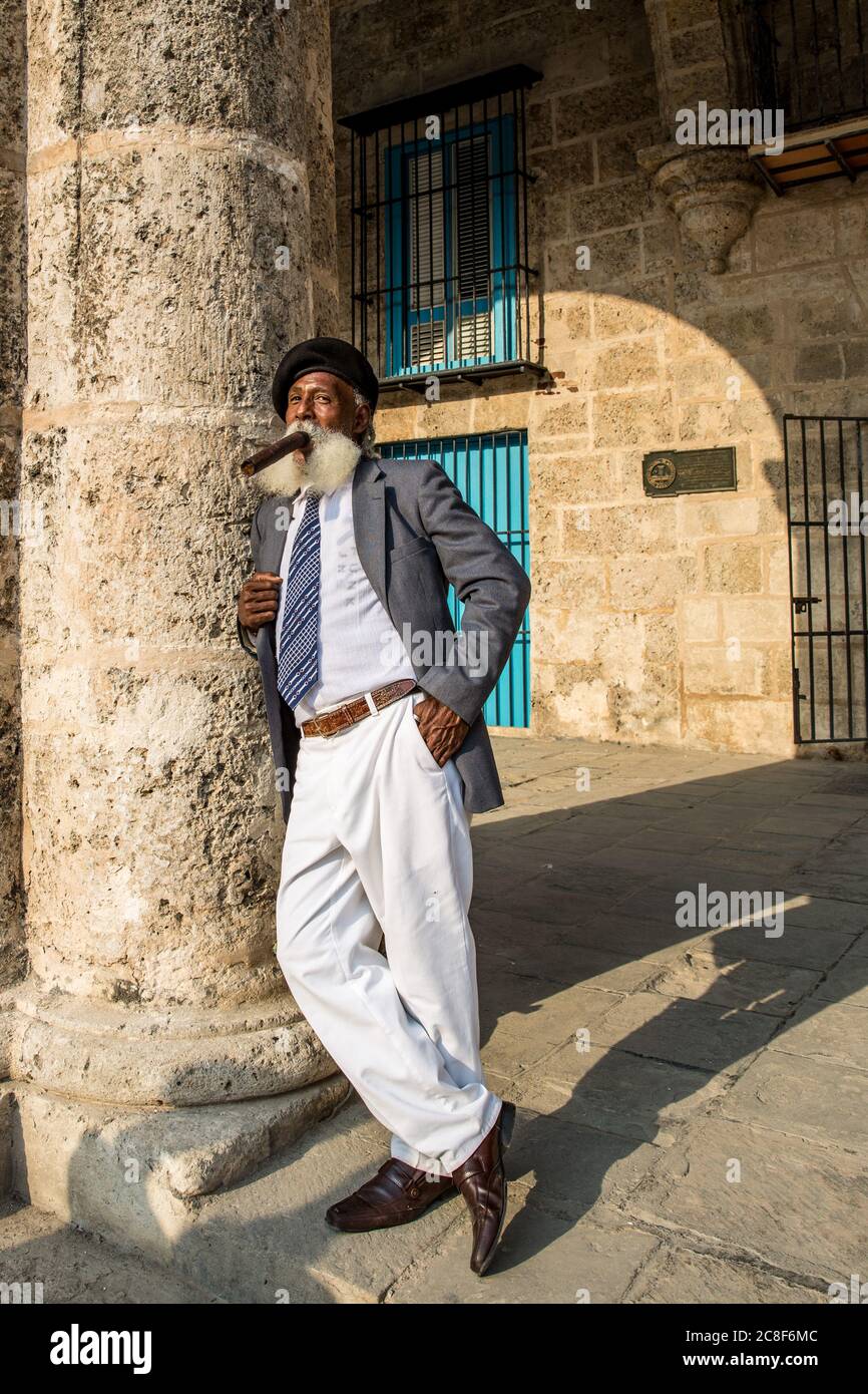 La Havane / Cuba - 04.16.2015: Afro cuban vieux avec une longue barbe blanche portant un costume et un béret militaire noir, fume un gros cigare Banque D'Images