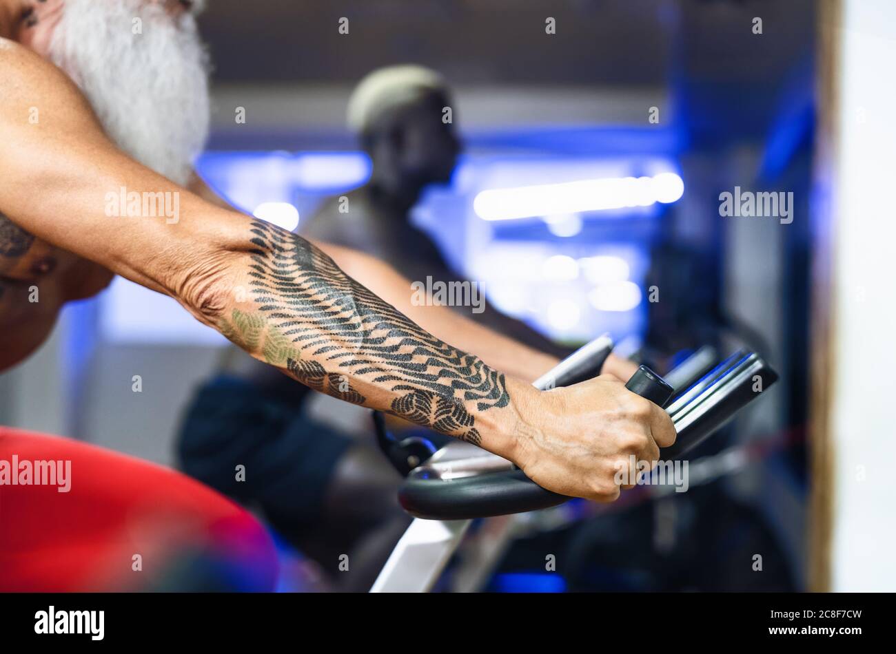 Senior homme faisant des exercices de vélo dans la salle de gym - mature fitness masculin sur la machine à vélo dans le centre de bien-être de santé Banque D'Images