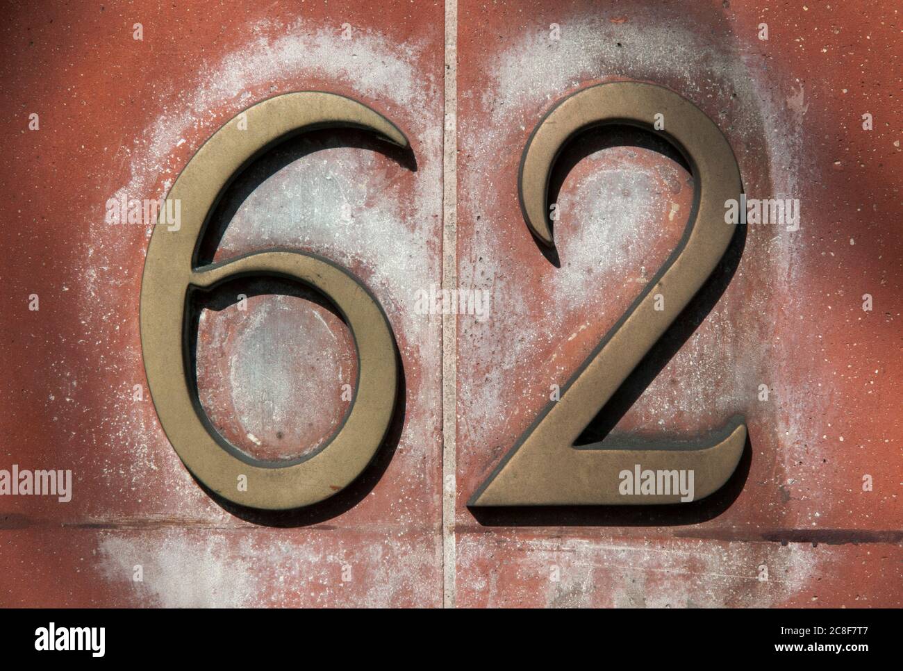 Gros plan du numéro 62 en laiton sur UN mur en terre cuite Banque D'Images