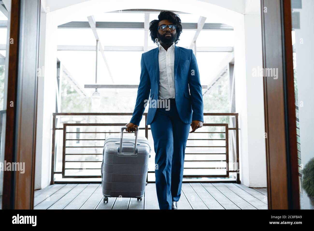 Homme noir en costume habillé avec une valise emballée entrant dans la ...