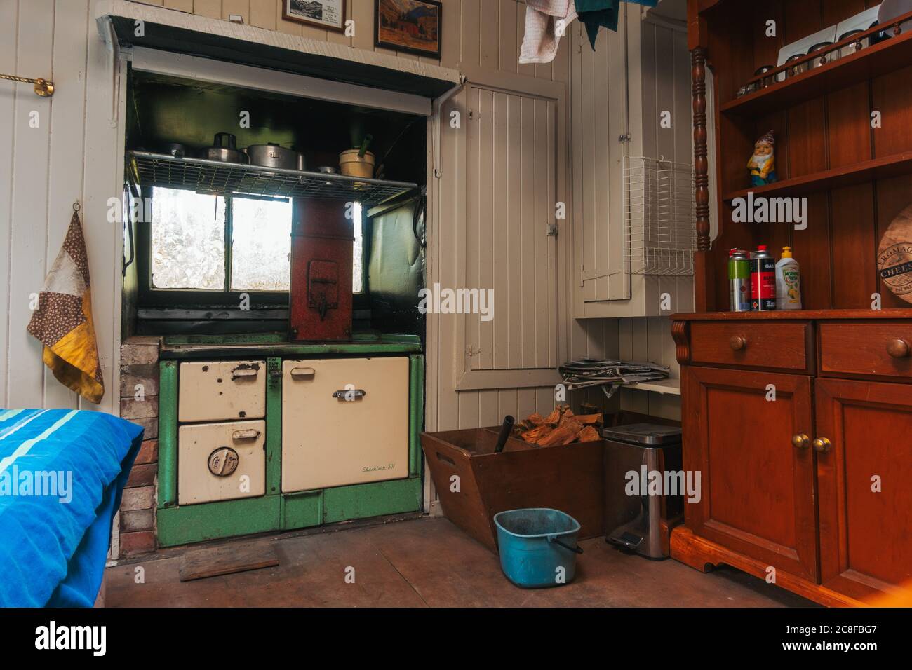 Intérieur d'une petite cabane restaurée dans le Bush en Nouvelle-Zélande. Un brûleur à bois classique / charbon de la gamme Shacklock 501 poêle est vu dans le mur Banque D'Images