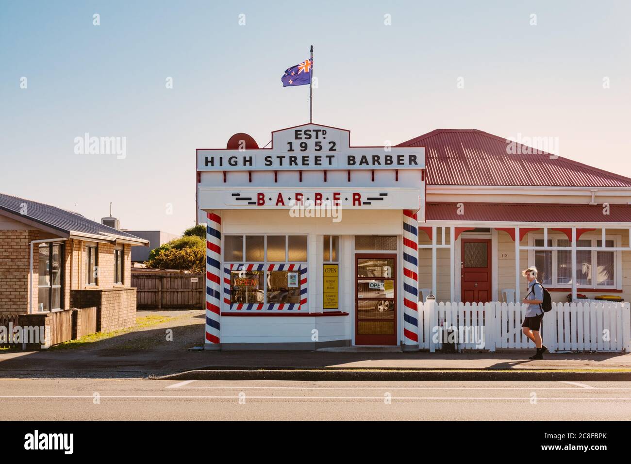 Un garçon d'école passe devant un salon de coiffure High Street de style des années 1950 à Greymouth, en Nouvelle-Zélande Banque D'Images