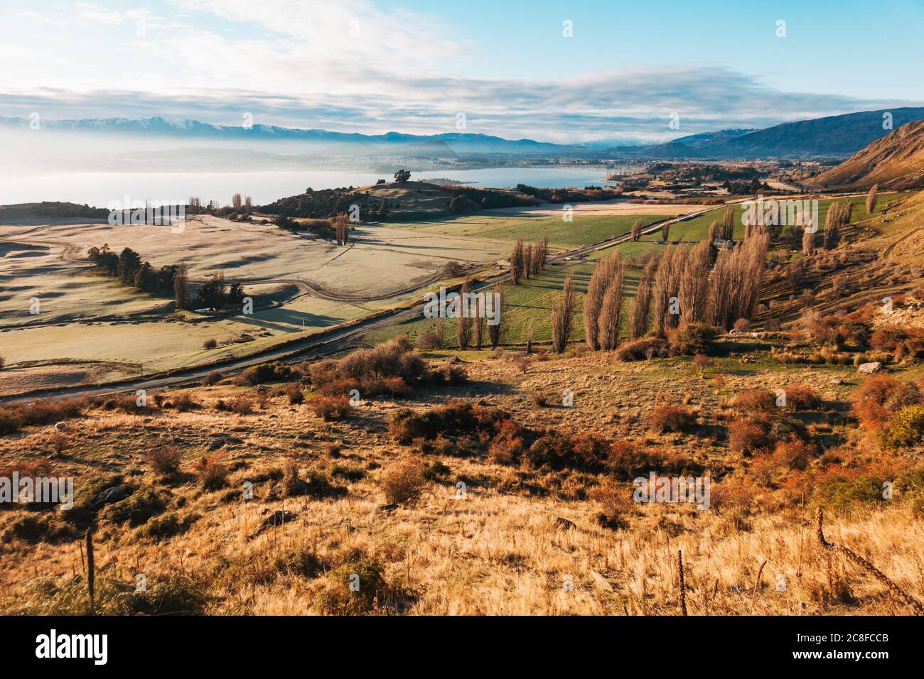 Le soleil s'élève sur des terres fertiles et des arbres d'automne au lac Wanaka, vu de Roys Peak Track, en Nouvelle-Zélande Banque D'Images