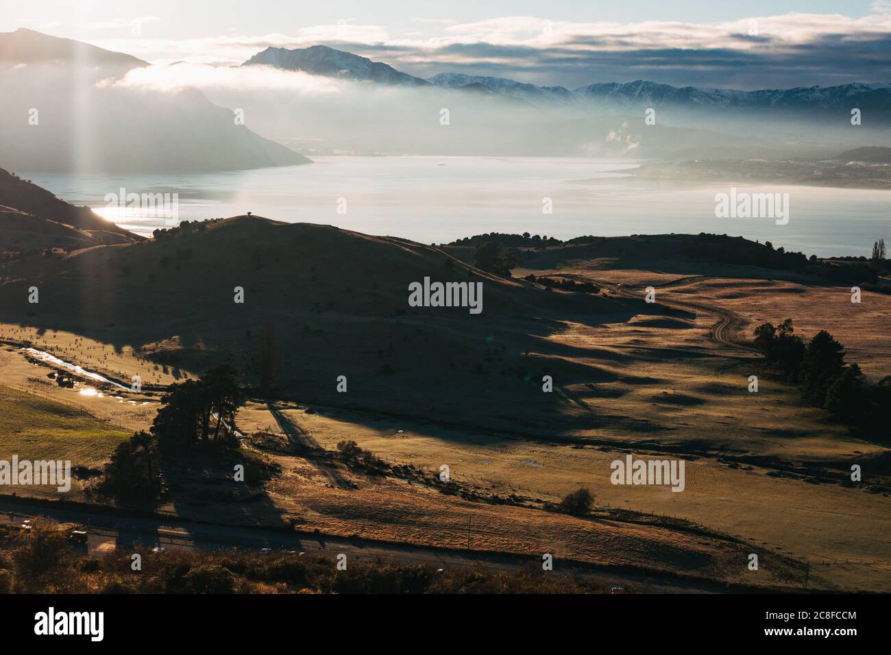 Le soleil s'élève sur des terres fertiles et des arbres d'automne au lac Wanaka, vu de Roys Peak Track, en Nouvelle-Zélande Banque D'Images