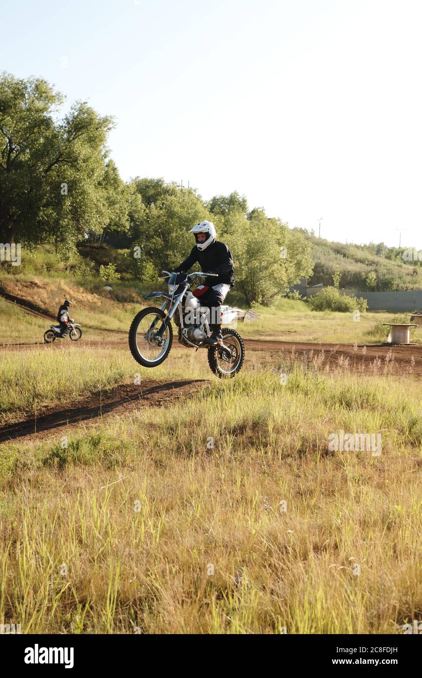 Un motocycliste professionnel en casque fait un pas en avant tout en conduisant une moto sur une piste difficile Banque D'Images