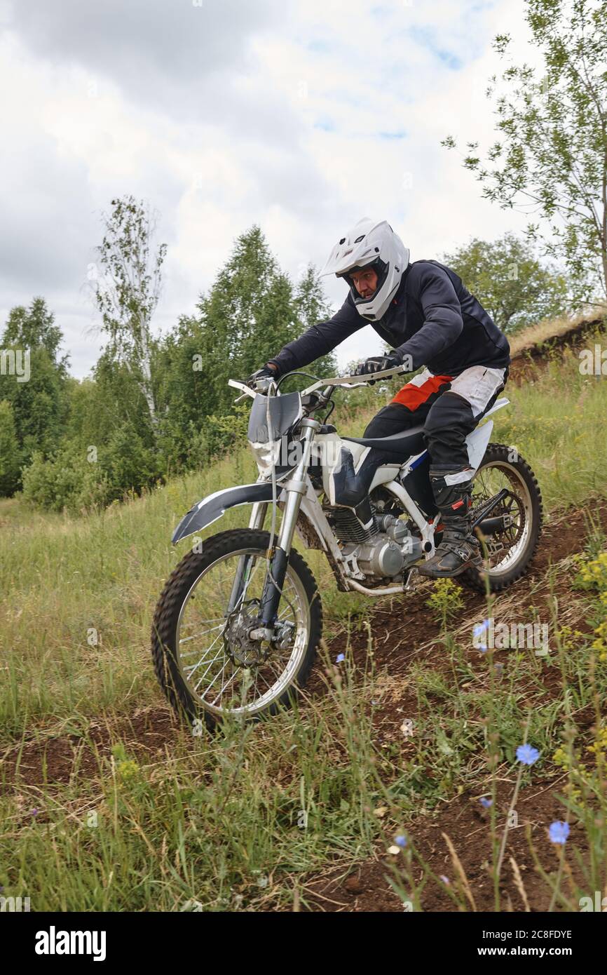 Homme concentré dans un casque qui pèse en arrière en roulant en descente de moto Banque D'Images