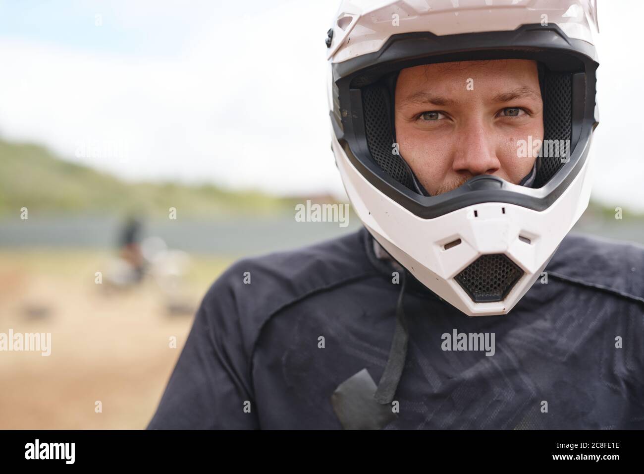 Portrait d'un jeune cycliste sérieux, casque blanc, sur piste tout-terrain Banque D'Images
