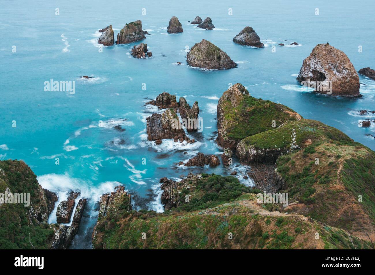Les vagues se cassent doucement contre une grande forme de roche à Nugget point / Tokata, Catlins Coast, Nouvelle-Zélande Banque D'Images