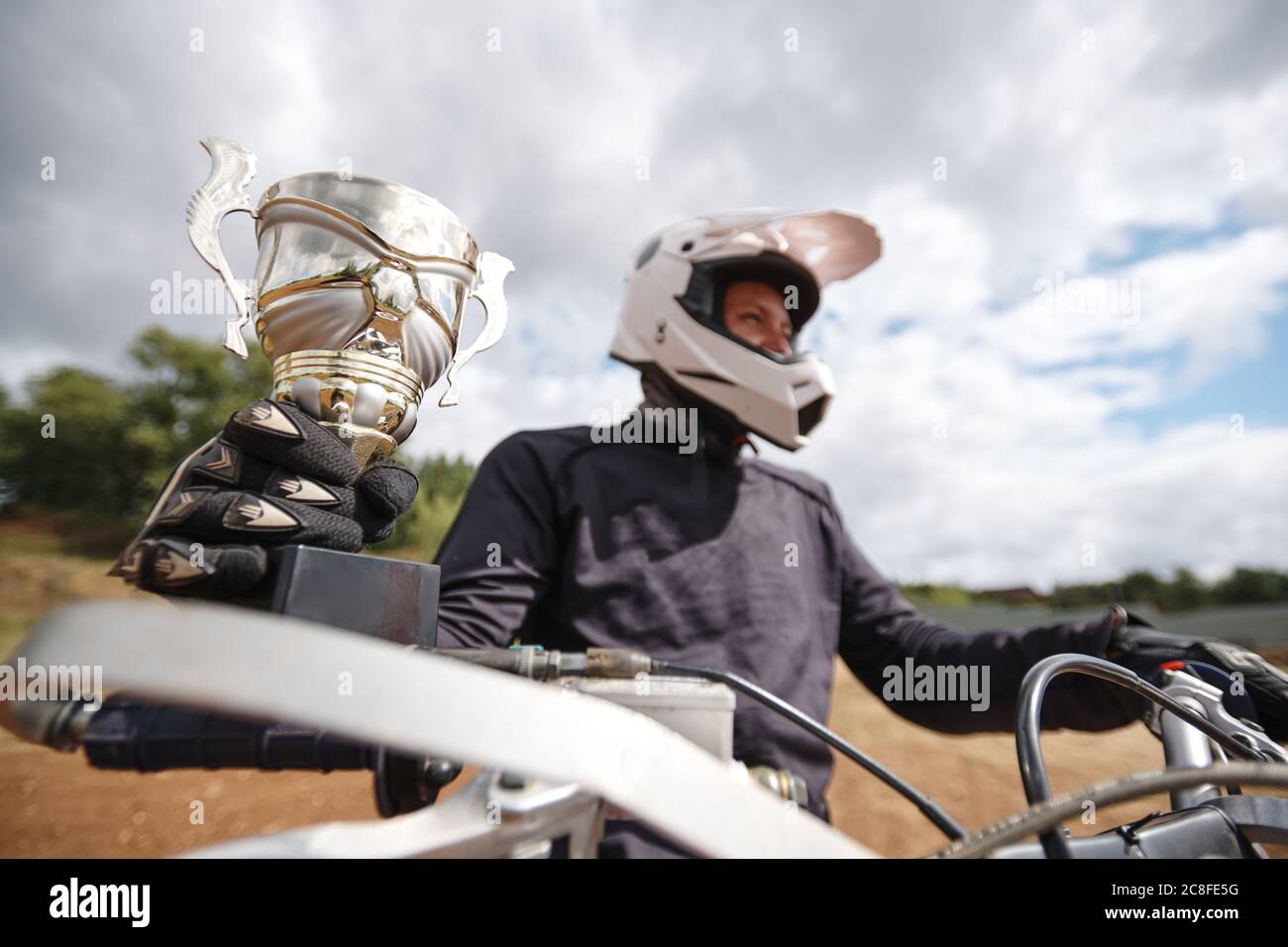 Gros plan d'un cycliste automobile réussi dans un casque gagnant de championnat de moto de moto de moto et de tenue de coupe Banque D'Images