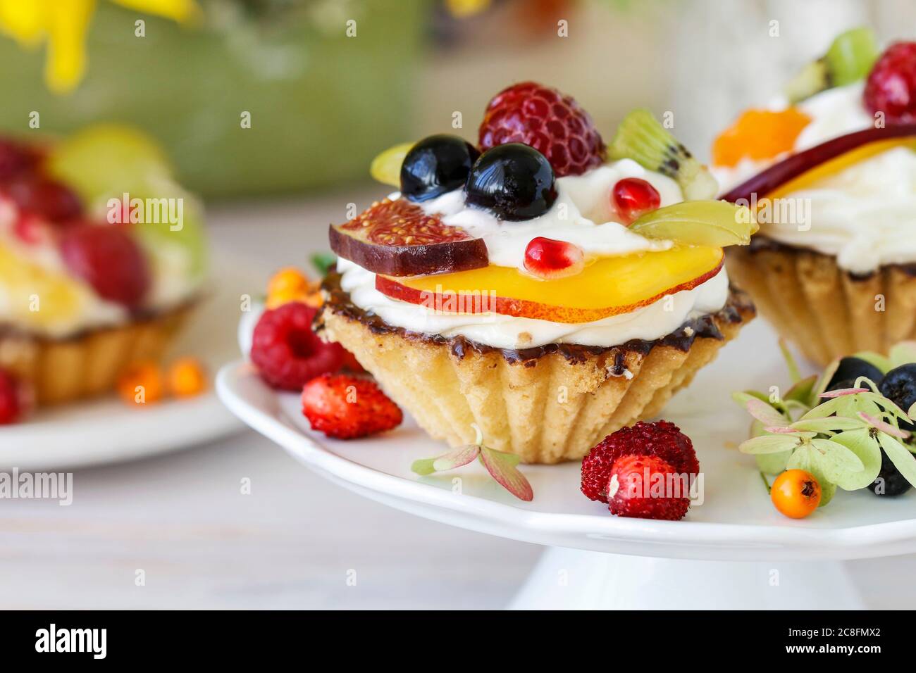 Petits gâteaux colorés et arrangements floraux avec tournesols et hortensias sur table de fête. Banque D'Images