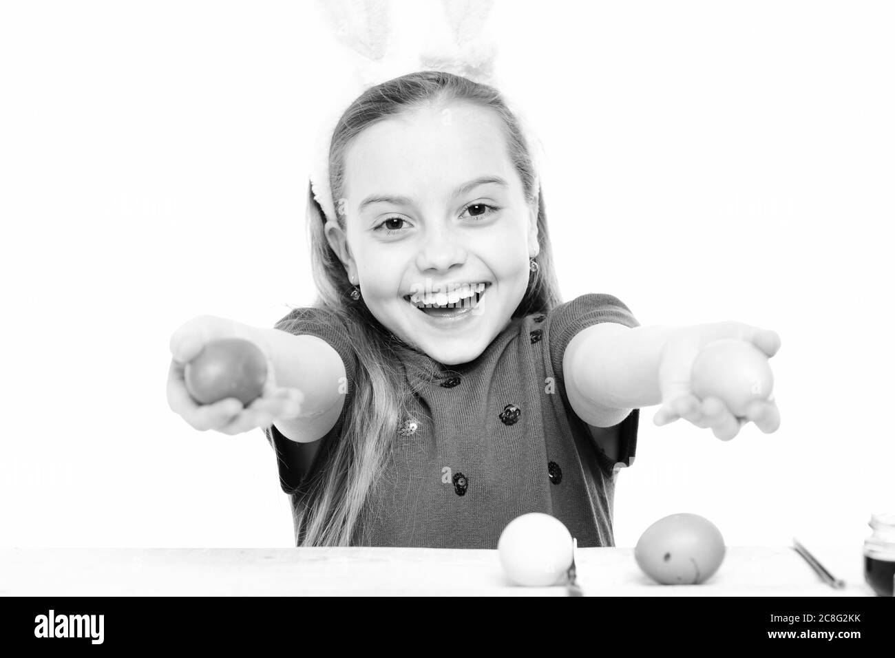 petite fille de bébé ou enfant mignon avec visage heureux portant des oreilles roses de lapin avec chemisier violet et tenant des œufs de pâques colorés isolés sur fond blanc Banque D'Images