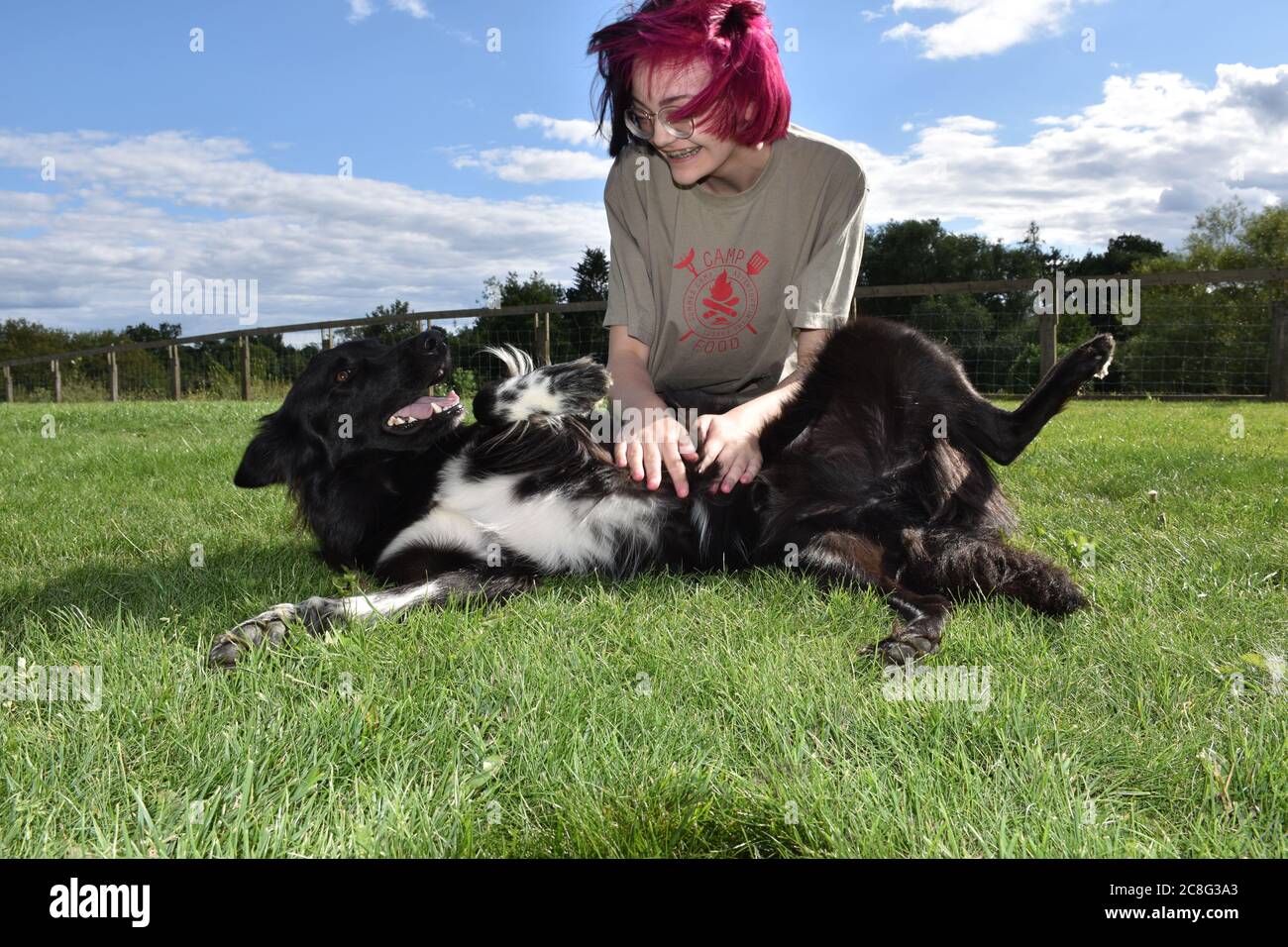 Fille jouant heureusement avec le chien dehors sur la pelouse au soleil d'été Banque D'Images