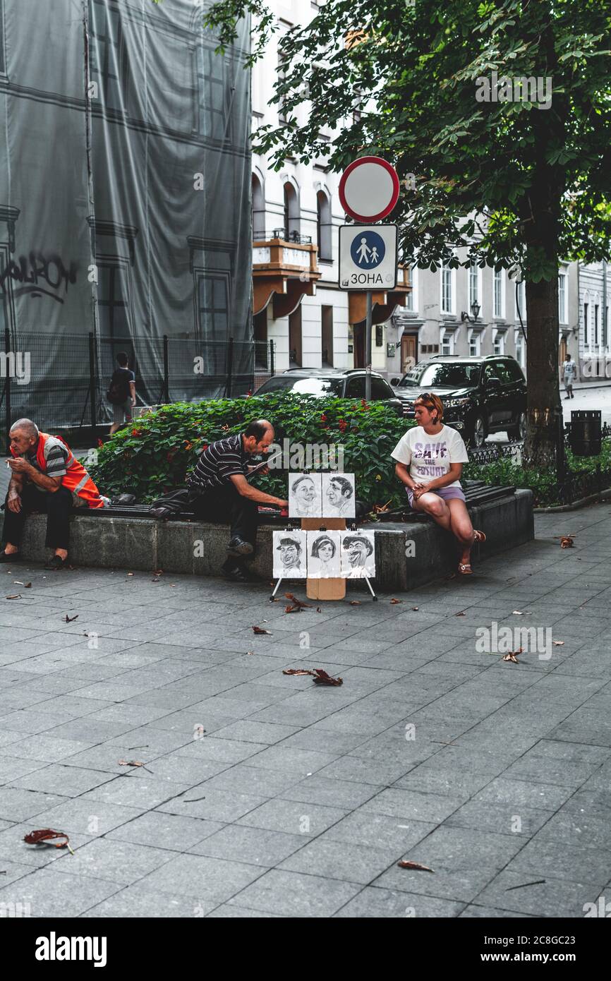 Ukraine, Odessa - 28 août 2019 : un caricaturiste de sexe masculin peint un portrait d'une femme dans la rue du boulevard Primorsky. Banque D'Images