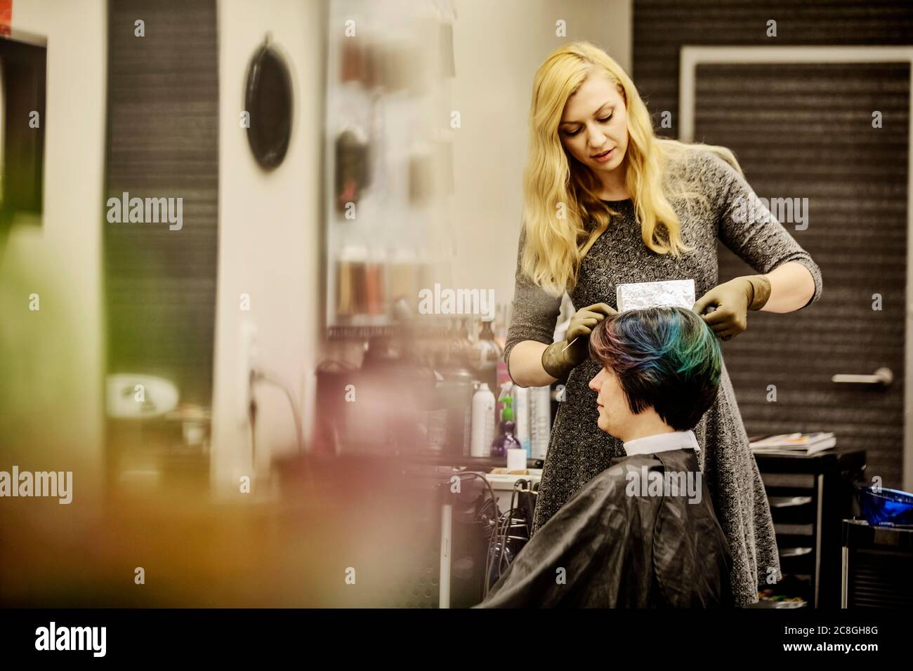 Coiffeur dans un salon de coiffure, moussant des mèches de cheveux avec du papier aluminium, Rhénanie-du-Nord-Westphalie, Allemagne Banque D'Images