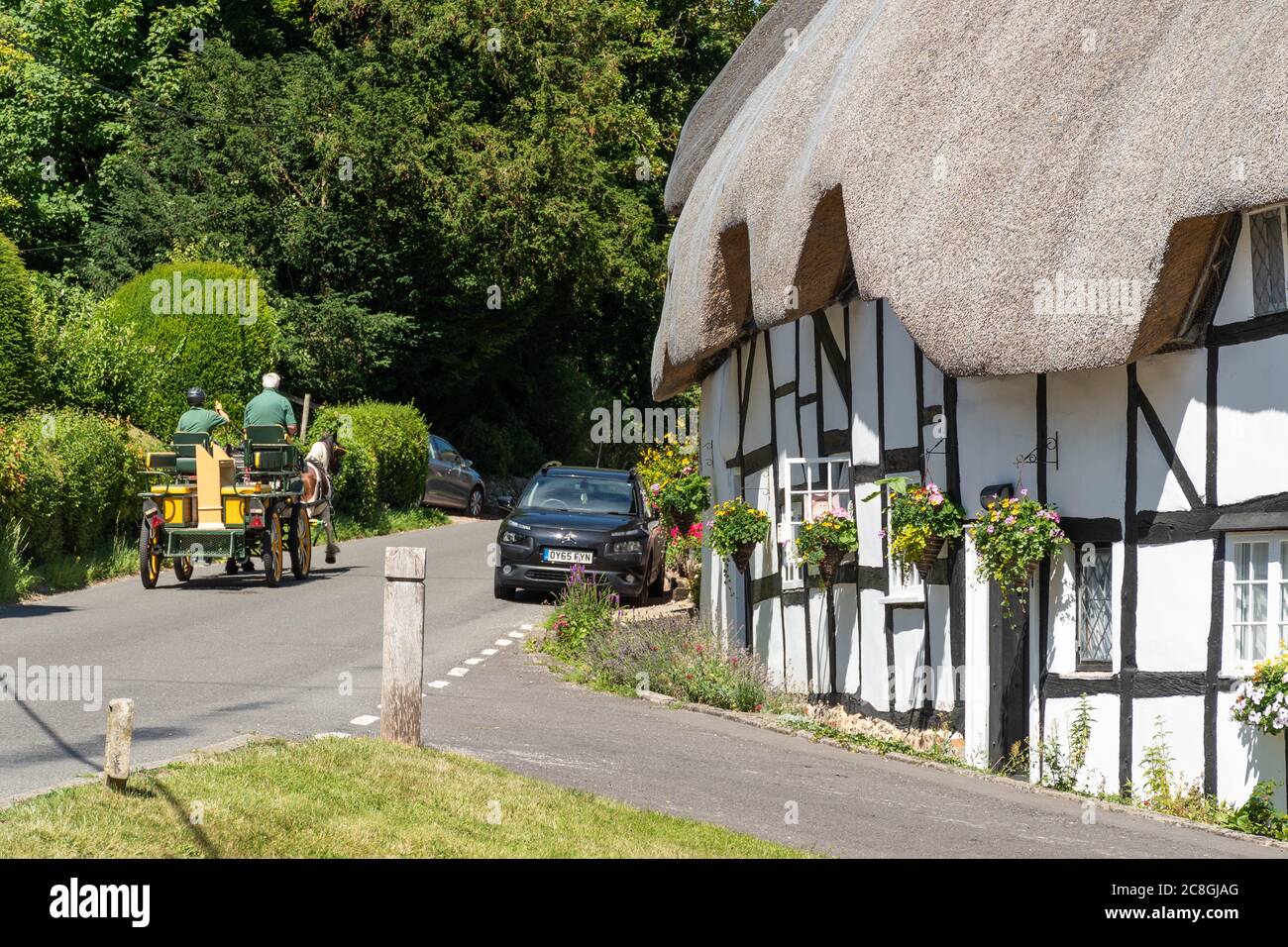 Jolies maisons de chaume dans le village Hampshire de Wherwell, Angleterre, Royaume-Uni, en été, avec un cheval et une voiturette passant Banque D'Images
